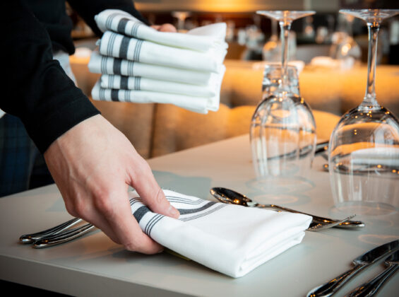 Black Stripe Bistro Style Napkin s being placed on a table